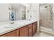 Bathroom featuring a double sink vanity with wood cabinets and a glass shower at 3002 Mojave Oak Dr, Valrico, FL 33594