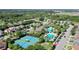 Aerial view featuring the tennis courts, community pool, clubhouse, palm trees, and surrounding neighborhood at 34244 Radley Way, Wesley Chapel, FL 33545