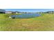 Expansive backyard with lush green grass, a picturesque pond, and a concrete structure near the water at 34311 Evergreen Hill Ct, Wesley Chapel, FL 33545