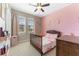 Charming bedroom with pink accent wall, ceiling fan, window, and a wooden crib at 34311 Evergreen Hill Ct, Wesley Chapel, FL 33545