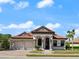 Charming single-story home featuring a red tile roof, arched entryway, and a two-car garage set against a sunny sky at 3635 80Th E Dr, Sarasota, FL 34243