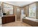 This bathroom offers dual vanities, a walk-in shower and a garden tub beneath a window with natural light at 5305 Sagecrest Dr, Lithia, FL 33547