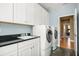 A Laundry room including a washer and dryer, white cabinetry, and a utility sink with a black countertop at 5305 Sagecrest Dr, Lithia, FL 33547