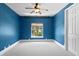 Bright bedroom boasts blue walls, plush carpeting, a ceiling fan, and a window with a scenic view at 708 Islebay Dr, Apollo Beach, FL 33572