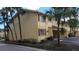 Exterior of the condo with yellow walls, brown trim, and some palm trees and patchy grass at 7502 Bolanos Ct, Tampa, FL 33615