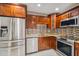 A well-lit kitchen featuring stainless steel appliances, granite countertops and brown wood cabinets at 7512 Dolonita Dr # 7512, Tampa, FL 33615