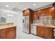 A kitchen featuring updated appliances, wood cabinets, granite countertops, and white tile floors at 7512 Dolonita Dr # 7512, Tampa, FL 33615