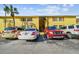 View of the parking lot in front of a yellow apartment building with parking spaces and parked cars at 7512 Dolonita Dr # 7512, Tampa, FL 33615