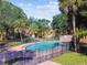Exterior shot of the community pool surrounded by a black metal fence, grassy areas, and mature trees at 7512 Dolonita Dr # 7512, Tampa, FL 33615