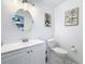 Bathroom featuring white fixtures, a round mirror, and botanical artwork on the wall at 777 62Nd N Ave, St Petersburg, FL 33702