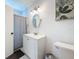 Bathroom featuring a white vanity, round mirror, three-light vanity light, and a tiled shower at 777 62Nd N Ave, St Petersburg, FL 33702
