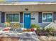 A brightly painted blue front door is framed by fresh landscaping, contrasting shutters, and light-colored siding at 777 62Nd N Ave, St Petersburg, FL 33702