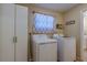 Laundry room with washer, dryer, cabinet, patterned curtains and neutral colored walls at 8740 Forest Lake Dr, Port Richey, FL 34668