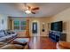 Spacious living room with hardwood floors, featuring a comfortable grey sofa and a large window at 8740 Forest Lake Dr, Port Richey, FL 34668