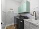 Well-equipped laundry room featuring modern washer/dryer, overhead cabinets, stylish wallpaper, and functional sink area at 9402 59Th N St, Pinellas Park, FL 33782