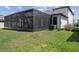 Back exterior view of screened in patio with grill, seating, and well-maintained backyard at 9817 Coneflower Ct, Land O Lakes, FL 34637