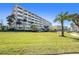 Exterior shot of the condo building highlighting a well-manicured lawn and palm trees at 100 Bluff View Dr # 614A, Belleair Bluffs, FL 33770