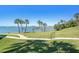 Green lawn with palm trees, walkway, and waterfront views with pier at 100 Bluff View Dr # 614A, Belleair Bluffs, FL 33770