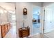 Bright bathroom with a double sink vanity and tile floors; bathtub with shower visible in the background at 10100 Grove Dr, Port Richey, FL 34668