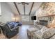 Cozy living room with stone fireplace, beamed vaulted ceiling, and comfortable seating at 10100 Grove Dr, Port Richey, FL 34668