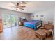 Spacious main bedroom featuring wood floors, a ceiling fan, and sliding glass door at 10100 Grove Dr, Port Richey, FL 34668