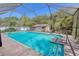 Screened-in pool and patio area with a clear blue pool and bright outdoor light at 10100 Grove Dr, Port Richey, FL 34668
