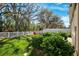 The backyard features a white vinyl fence, lush green grass, bushes and trees, with a view of the woods at 13001 Satin Lily Dr, Riverview, FL 33579