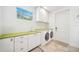 Bright laundry room with green countertops, white cabinets, and modern washer and dryer at 145 16Th Ne Ave, St Petersburg, FL 33704