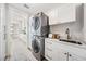 Well-lit laundry room features stackable washer/dryer, white cabinets and sink with modern faucet at 16327 Redington Dr, Redington Beach, FL 33708