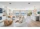 Bright open-concept living and dining area, featuring wood floors, large windows, and chic modern furniture at 16327 Redington Dr, Redington Beach, FL 33708