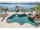 A freeform pool with an attached jacuzzi, a custom stone waterfall and a dock along a waterfront at 16327 Redington Dr, Redington Beach, FL 33708