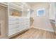 Bright walk-in closet features custom shelving, drawers, and wood-look flooring at 16327 Redington Dr, Redington Beach, FL 33708
