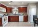 Well-lit kitchen featuring wood cabinetry, white appliances, granite countertops, tile flooring, and a breakfast bar at 1883 Fuller Dr, Clearwater, FL 33755