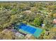 Aerial view of the property featuring a tennis court, pool, and mature trees providing plenty of shade at 2112 Laurence Dr, Clearwater, FL 33764