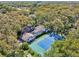 An aerial view shows a large home with a screened pool, tennis court, and mature trees at 2112 Laurence Dr, Clearwater, FL 33764