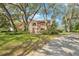 Exterior view of a beautiful home with mature trees, lush lawn, and winding driveway at 2112 Laurence Dr, Clearwater, FL 33764