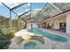 Enjoy this screened-in pool and spa surrounded by beautiful landscaping, with an outdoor kitchen and lounge area at 2112 Laurence Dr, Clearwater, FL 33764