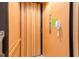 A wooden elevator with an accordion-style door and emergency phone inside the residence at 250 Seagate Ct, Dunedin, FL 34698