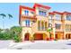 Exterior view showcasing the home's colorful facade, multiple balconies, and tropical landscaping at 250 Seagate Ct, Dunedin, FL 34698