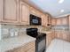 Modern kitchen with black appliances, granite countertops, and oak cabinets, accented by tile flooring at 3105 S Canal Dr, Palm Harbor, FL 34684