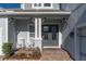 Charming front porch with rocking chairs, a gray double door entry, brick steps and trim, and a nice garden at 4204 Bonfire Dr, Odessa, FL 33556