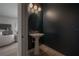 Elegant powder room featuring dark blue walls, a pedestal sink, and modern lighting fixtures at 5351 Bridge St # 99, Tampa, FL 33611