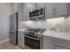 Up close kitchen showcasing stainless steel appliances, tile backsplash, and gray cabinets at 5351 Bridge St # 99, Tampa, FL 33611