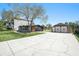 Exterior view of a home with long driveway leading to the metal and stone garage at 5560 Frances Ave, New Port Richey, FL 34653