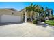 Beautiful home with white columns, arched entryway, attached garage, and a driveway surrounded by palm trees and landscaping at 609 Osceola Rd, Belleair, FL 33756