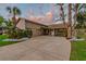 Inviting single-story house with meticulous landscaping, featuring palms and other lush greenery, with a grey sky at 6109 Schooner Way, Tampa, FL 33615