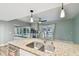 Open kitchen with granite island, stainless steel sink, and access to outdoor pool area at 6109 Schooner Way, Tampa, FL 33615