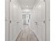 Hallway with wood-look tile, leading to bathroom, flanked by white doors at 706 Bayway Blvd # 301, Clearwater Beach, FL 33767
