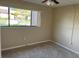 A bedroom with neutral carpeting, a large window providing natural light, and a ceiling fan at 730 S Village N Dr # 101, St Petersburg, FL 33716