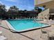 Fenced community swimming pool with plenty of lounge chairs and tables for residents to enjoy at 730 S Village N Dr # 101, St Petersburg, FL 33716